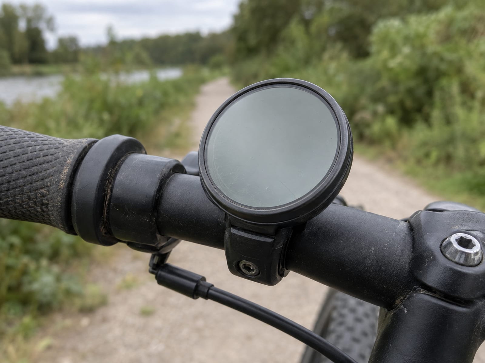Close-up of a bicycle speedometer with a blank face mounted on dark handlebars
